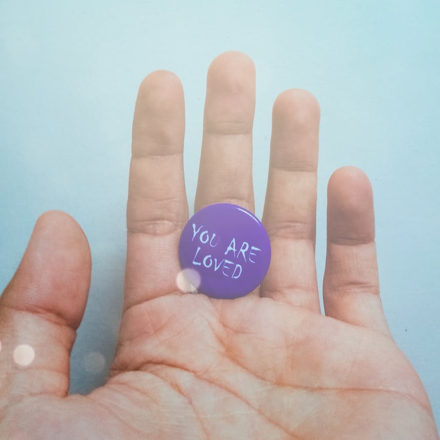 person holding purple badge you are loved text printed